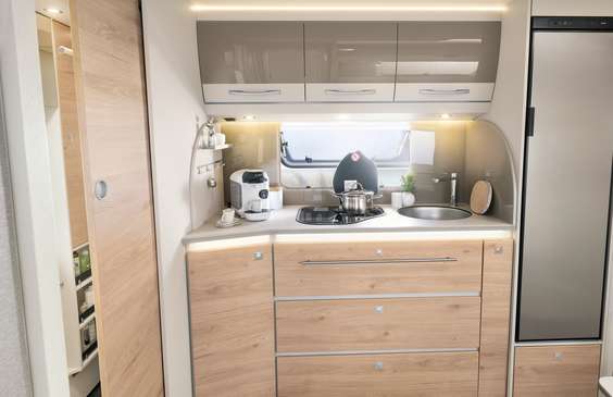 Obszerna kuchnia z praktyczną szufladą pionową, miejscem na ekspres do kawy, kuchenką 3-palnikową z elektrycznym zapalnikiem oraz podświetlaną ścianą kuchenną • 520 ELT | Ruby